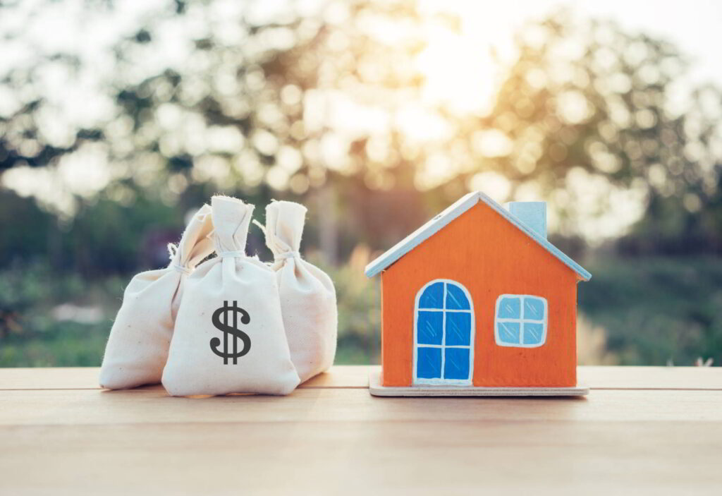 House model and money bags in savings Coins on table for finance and banking concept.